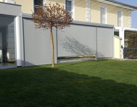 Eine Terrasse mit einem Glasdach und Glasschiebetüren mit Senkrechtbeschattung