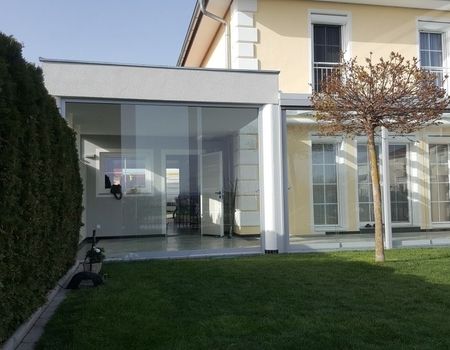 Eine Terrasse mit einem Glasdach und Glasschiebetüren