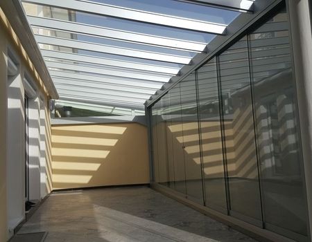 Eine Terrasse mit einem Glasdach und Glasschiebetüren