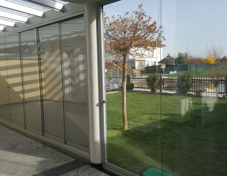 Eine Terrasse mit einem Glasdach und Glasschiebetüren