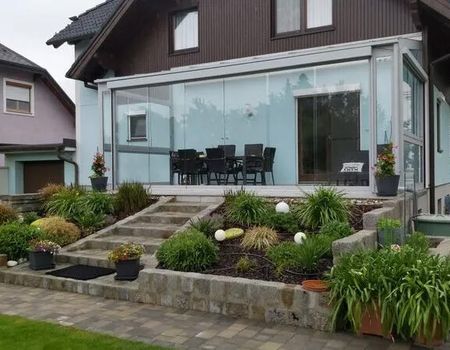 Eine Terrasse mit Sommergarten und Blumenbeete im Vordergrund