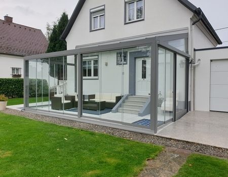 Ein großer Sommergarten mit Glasschiebetüren  auf einer großen Terrasse