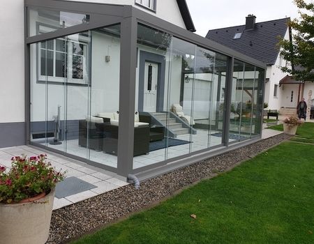 Ein großer Sommergarten mit Glasschiebetüren  auf einer großen Terrasse