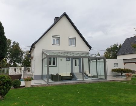 Ein großer Sommergarten mit Glasschiebetüren  auf einer großen Terrasse