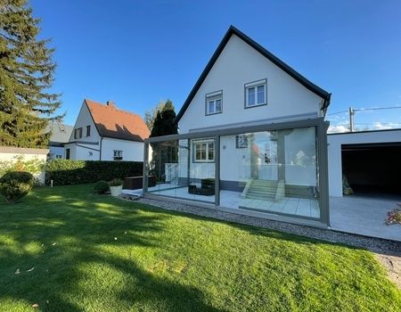 Ein großer Sommergarten mit Glasschiebetüren  auf einer großen Terrasse
