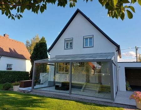 Ein großer Sommergarten mit Glasschiebetüren  auf einer großen Terrasse