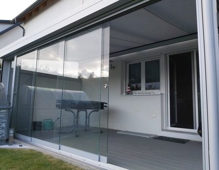 Ein Sommergarten mit Glasschiebetüren auf der Vorderseite, die halb geöffnet sind.