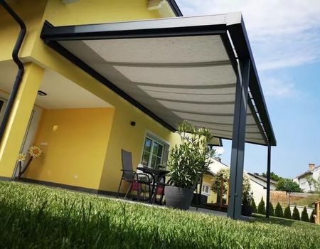 Ein gelbes Gebäude mit einer Terrassenüberdachung mit Unterglas-Markise