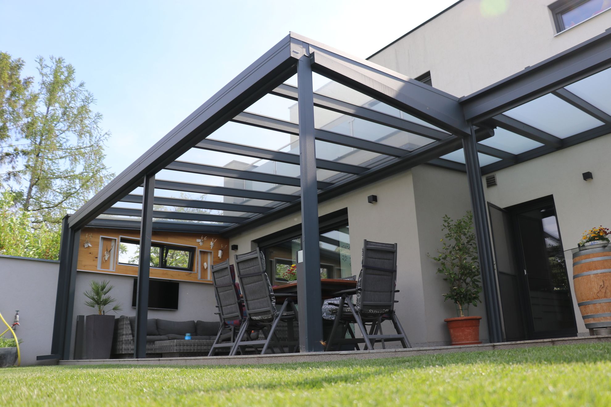 Eine Terrasse mit einem Glasdach und einem Grill, ideal für gesellige Abende im Freien.